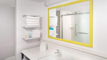 Un baño moderno con un lavamanos blanco, un espejo con marco amarillo y un perchero con toallas dobladas.