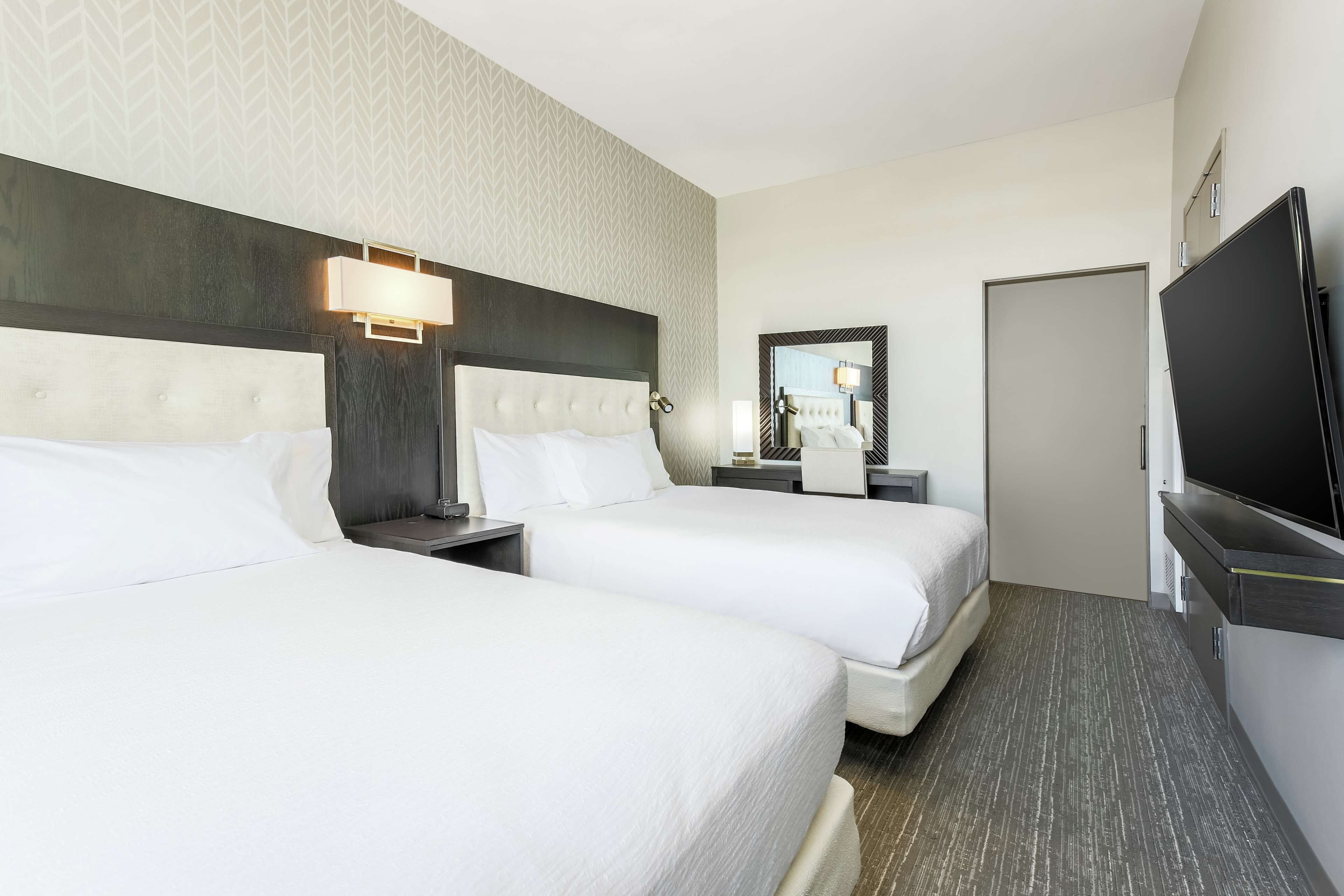 Una habitación de hotel con dos camas, un televisor, un espejo y una puerta.