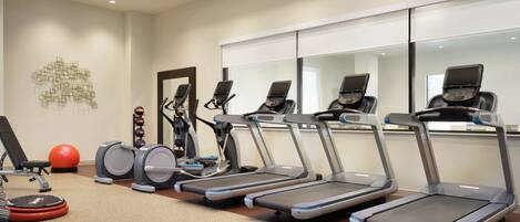 A gym with treadmills, weight machines, and exercise balls.