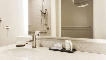 A hotel bathroom with a sink, mirror, and toiletries.