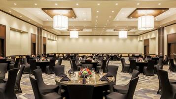 A conference room with round tables, black chairs, and chandeliers.