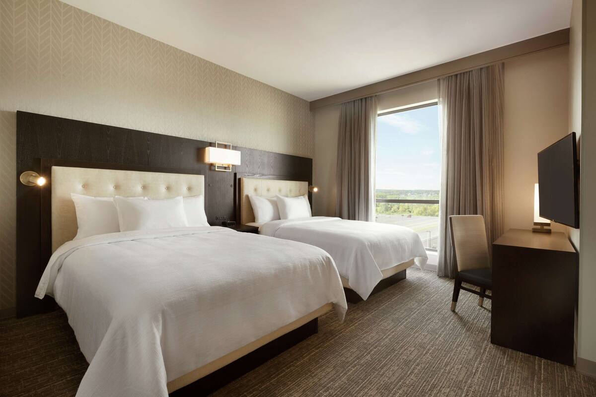 Een hotelkamer met twee bedden, een bureau en een televisie.