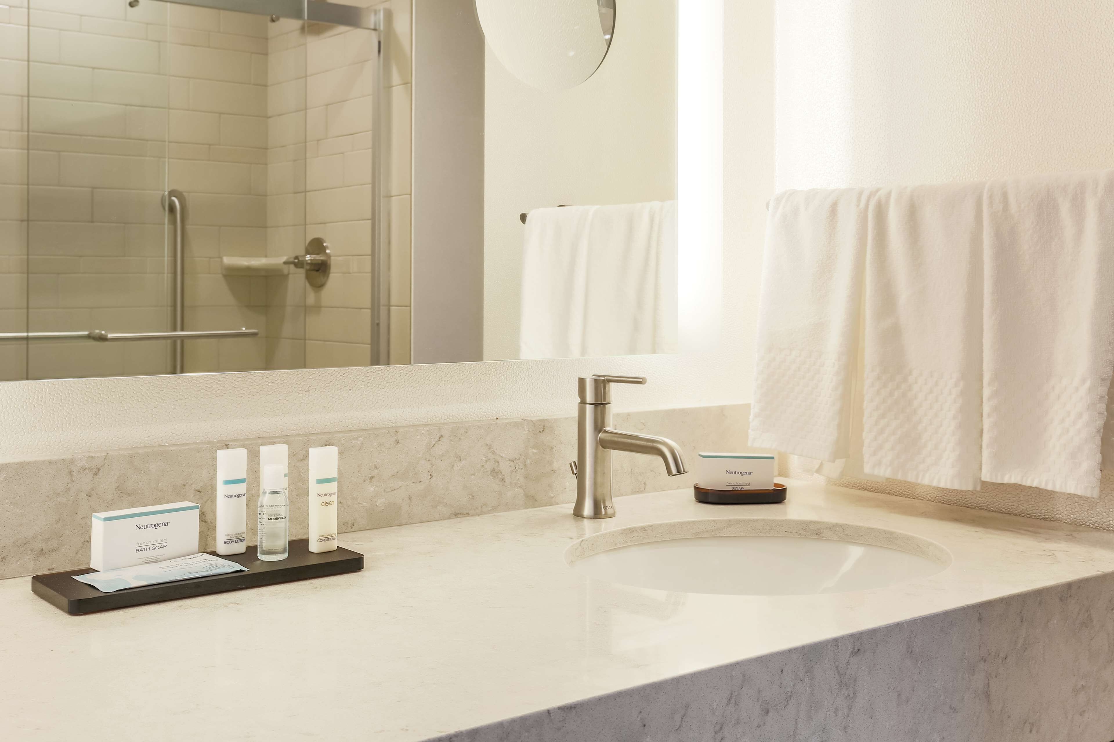 A bathroom with a sink, mirror, and toiletries.