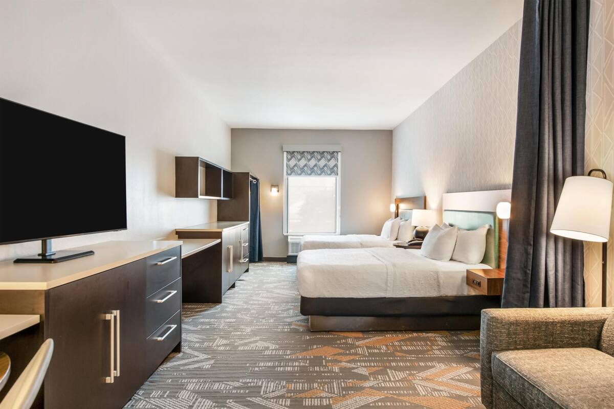 Ein Hotelzimmer mit einem Bett, einem Schreibtisch mit Fernseher, einem Sessel und einer Couch.