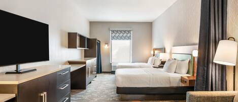 Une chambre d’hôtel avec un lit, un bureau avec une télévision, une chaise et un canapé.