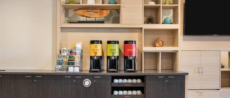 Una estación de café con tres cafeteras y una exhibición de tazas.