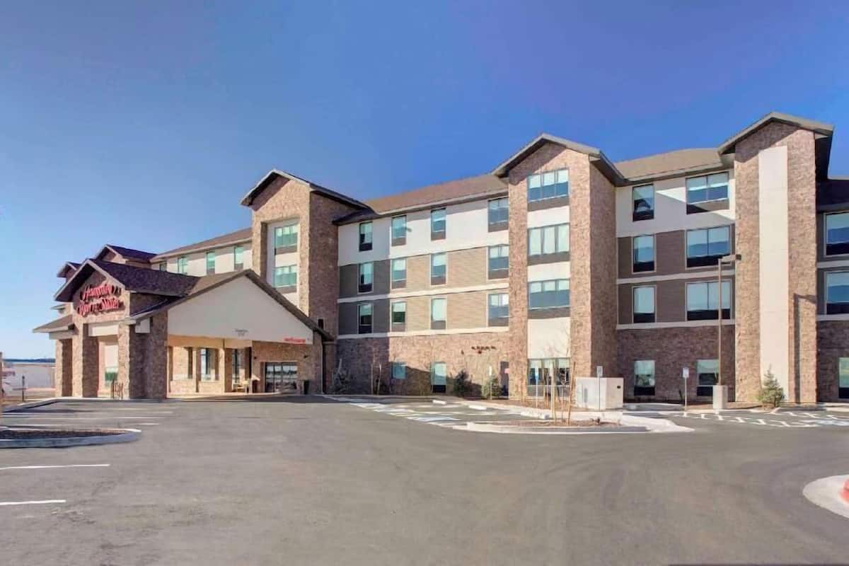 A multi-story hotel with a central entrance, large windows, and a parking lot.