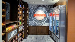 A grocery store aisle with shelves stocked with snacks and treats, a 'Treats' sign, and refrigerated display cases. - Hampton Inn & Suites Flagstaff East (Flagstaff)