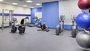 A gym with various exercise equipment including treadmills, stationary bikes, and exercise balls.