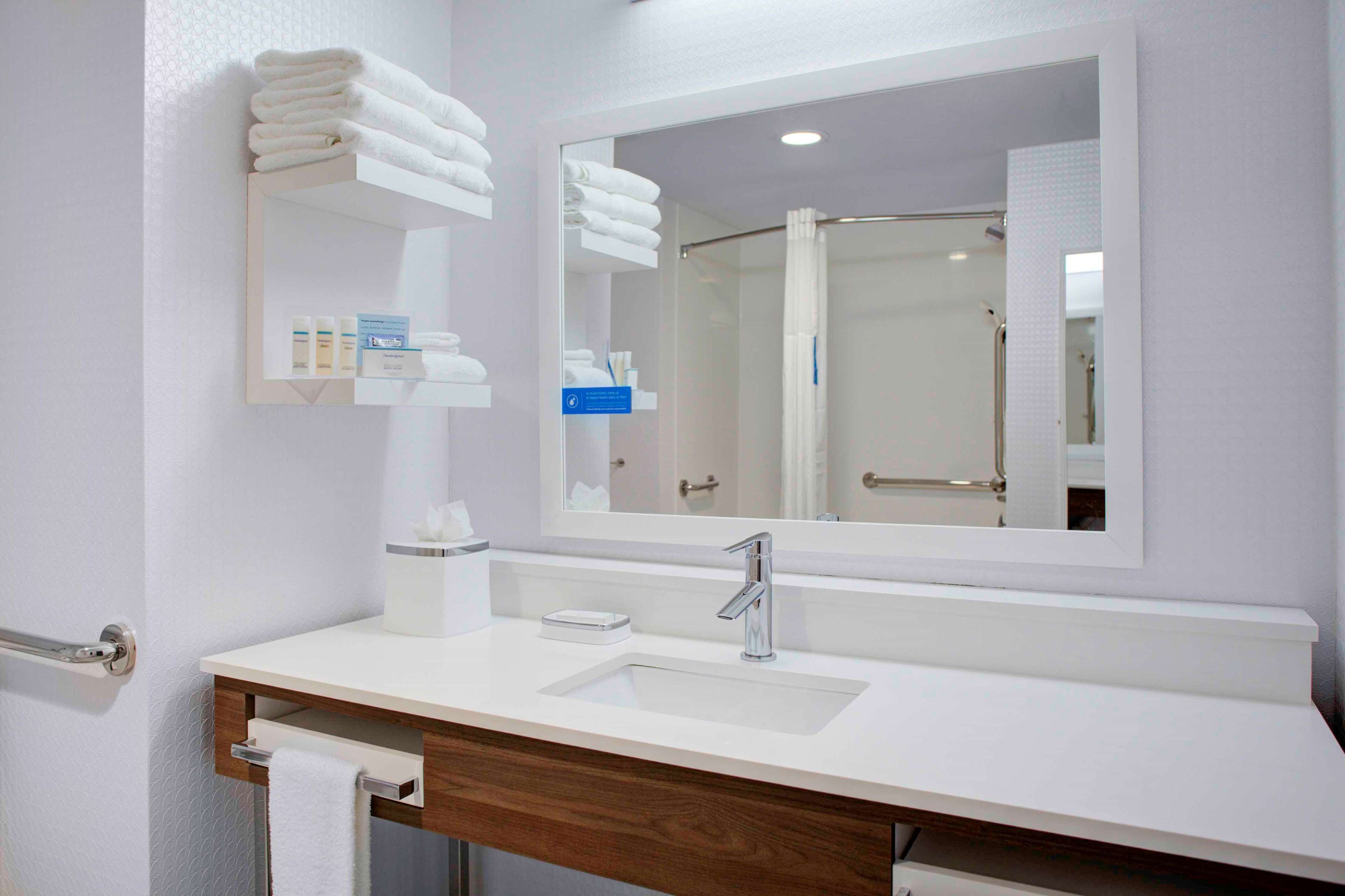 A modern bathroom with a white sink, a mirror, and a towel rack.