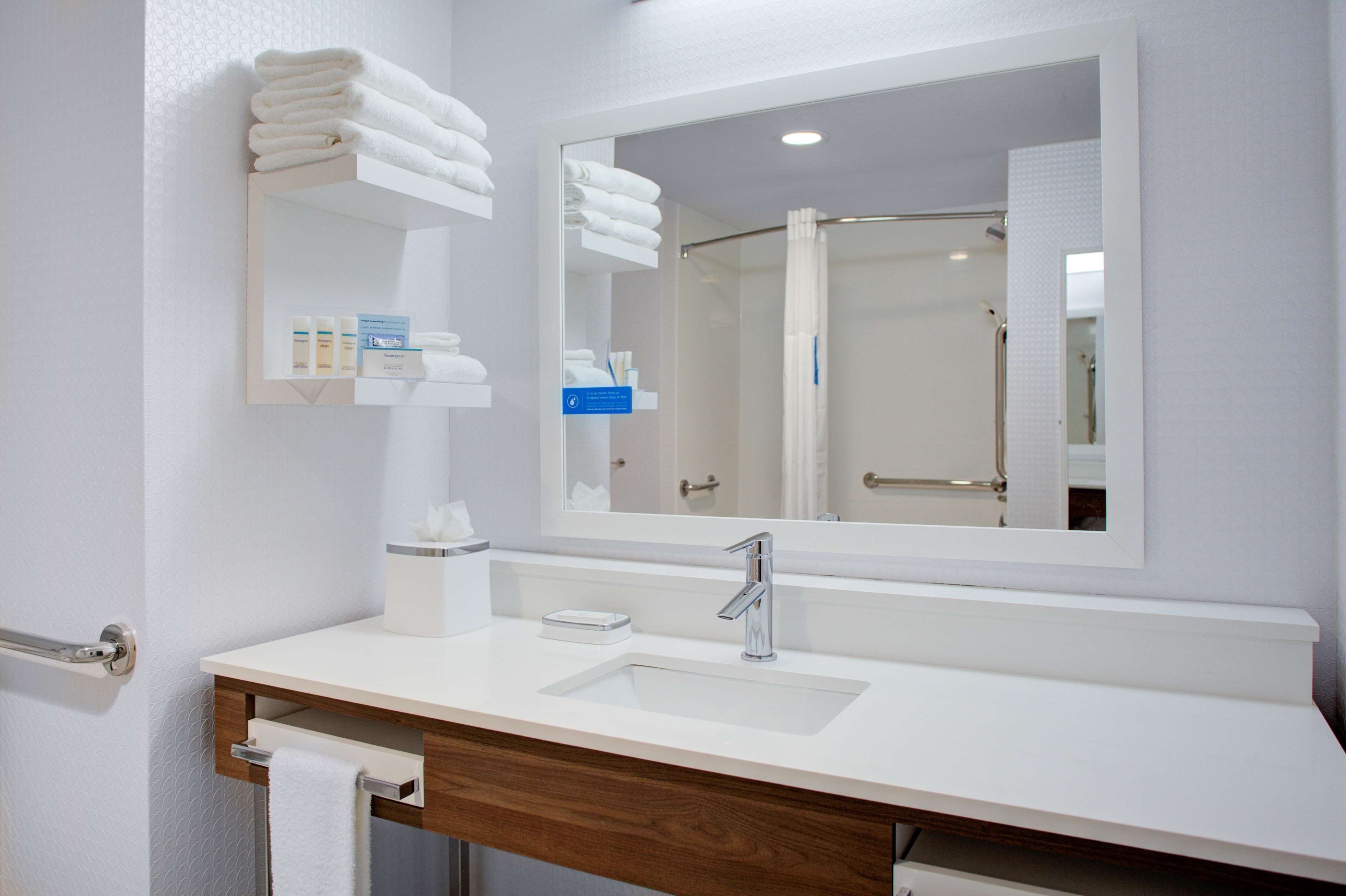A modern bathroom with a white sink, a mirror, and a towel rack.