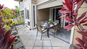 A patio with a table set for four, surrounded by potted plants and a stone pathway.