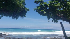 A coastal view with a clear sky, ocean waves, and a stone wall.