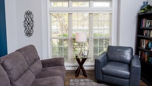 A living room with a gray sofa, a leather armchair, a glass coffee table, and a bookshelf. - Beautiful Large Two Story Condo Near The Beach With Unique Pricing! (North Myrtle Beach)