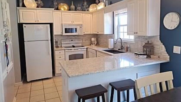 A kitchen with white cabinets, a refrigerator, a microwave, and a sink. - Beautiful Large Two Story Condo Near The Beach With Unique Pricing! (North Myrtle Beach)
