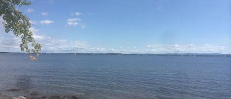 A beach with clear water, a sandy shore, and distant sailboats.