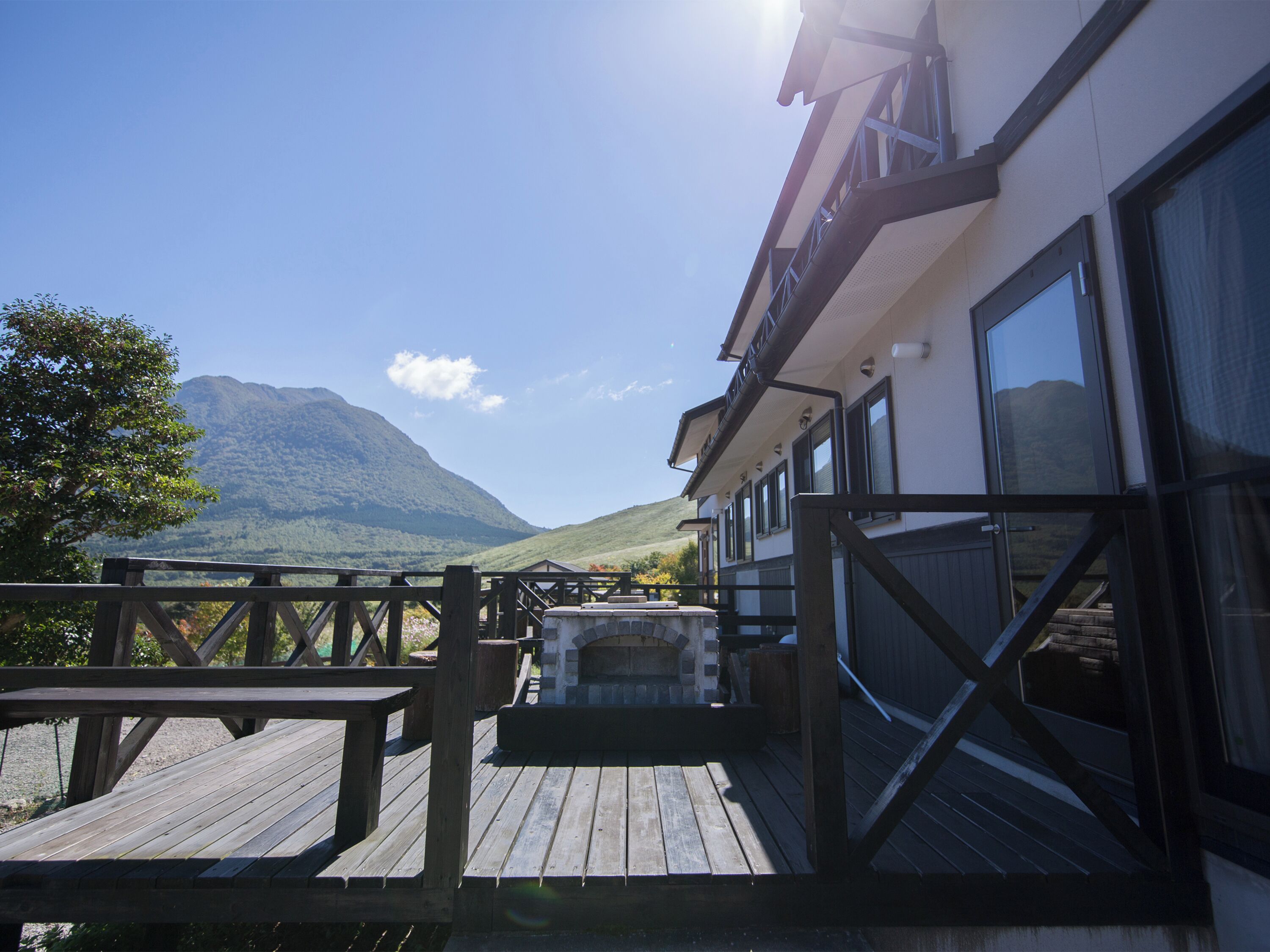 Una terraza de madera con un jacuzzi, con vistas a una cadena montañosa.