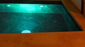 Ein Schwimmbecken mit gefliestem Boden und einem Metallgeländer.