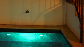 Une piscine avec un sol carrelé et une rambarde en métal.