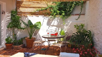 Un espace piscine agrémenté d’une table et de chaises, entouré de plantes en pot et surmonté d’un toit de chaume.