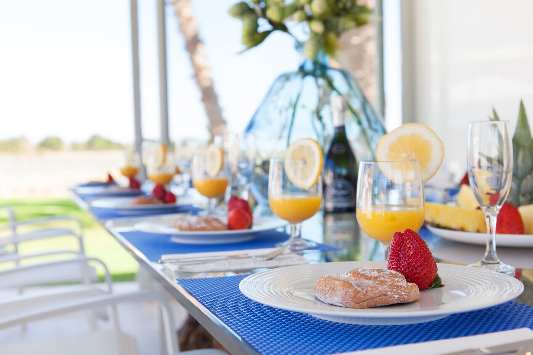 A breakfast table with plates of food, glasses of orange juice, and a bottle of water.