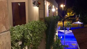 Ein Gebäude bei Nacht mit Poolanlage, umgeben von Grünflächen und beleuchtet durch hängende Lichter.