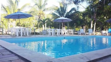 Una piscina al aire libre, sombrillas, sillones reclinables de piscina
