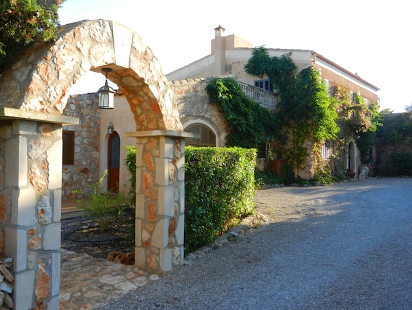 A stone archway leading to a building with a stone facade and ivy-covered walls.