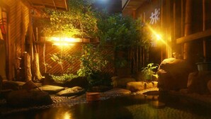 Un jardin japonais traditionnel avec une structure en bois, du bambou et un bassin à carpes koï.