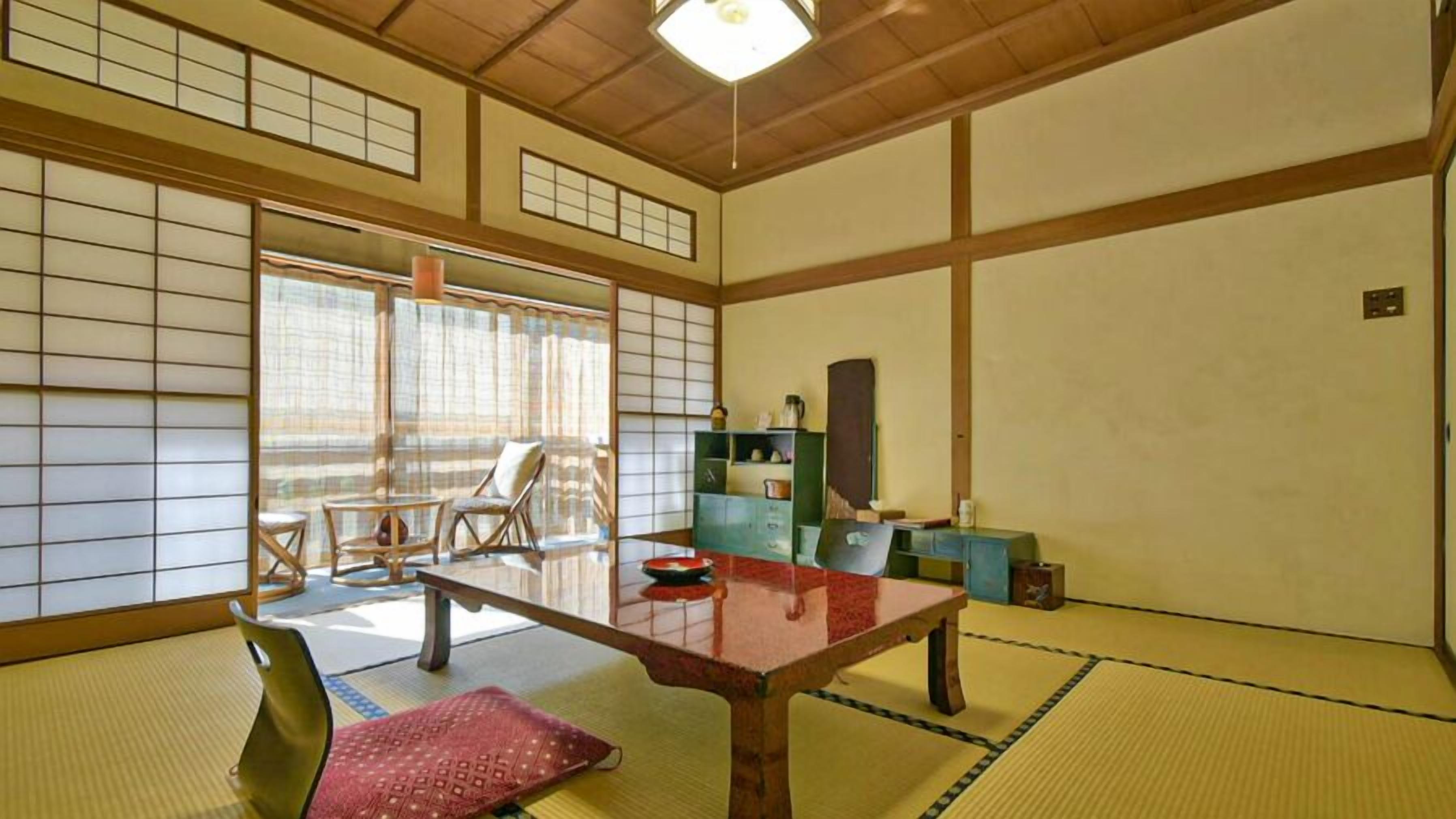 A traditional Japanese room with tatami flooring, a low table, and sliding doors.