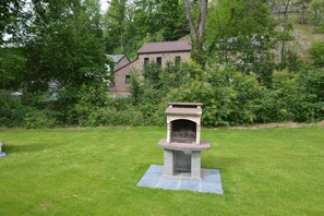 Enjoy gatherings around the central outdoor fireplace in a serene natural setting surrounded by lush greenery.