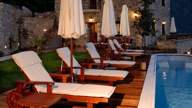 A stone building with a poolside area featuring sun loungers and umbrellas. - Miression Pelion House (Mouresi  Pelion)