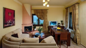 A living room with a sofa, a fireplace, a dining table, and a television. - Miression Pelion House (Mouresi  Pelion)