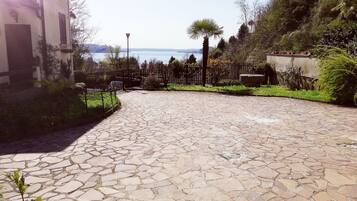 Un cortile pavimentato con piastrelle in pietra, una recinzione in metallo e vista sul mare.