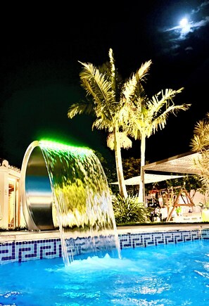 A pool with a water feature, palm trees, and a night sky. - RENOVATED 2026. BEACHFRONT. 5 MASTER SUITES. HEATED POOL. GAMES ROOM. (Marbella)