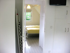 Une chambre à coucher avec un lit, une fenêtre et un téléviseur fixé au mur.