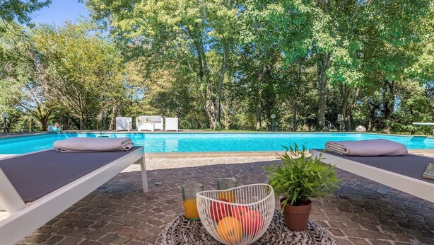A poolside area with lounge chairs and a fruit basket.