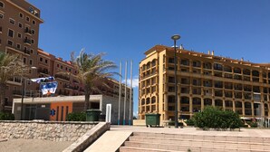 A multi-story hotel with balconies, a sandy ground area, and a street lamp. - First line of the sea - Port Saplaya (Alboraia)