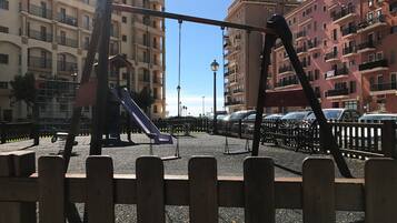 Children can play on the slide and swings in this enclosed playground area.