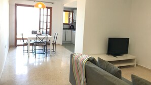 A modern living room with a grey sofa, a flat-screen TV, and a dining area with a table and chairs. - First line of the sea - Port Saplaya (Alboraia)