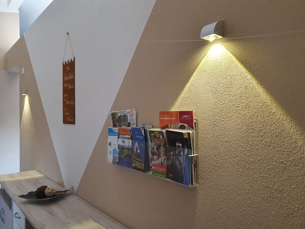 A wall with a bulletin board displaying various magazines and a sign.