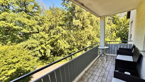 A balcony with a tiled floor, a small round table, and two wicker chairs. - Idyllic apartment in Friedrichshafen / Manzell NEW !!!! (Friedrichshafen)