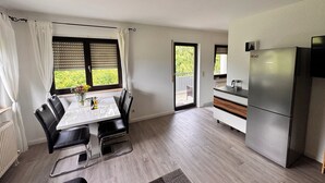 A modern kitchen with a Bosch refrigerator, a dining table with chairs, and a view through the window. - Idyllic apartment in Friedrichshafen / Manzell NEW !!!! (Friedrichshafen)
