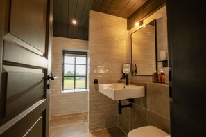 A bathroom with a white sink, a toilet, and a window.