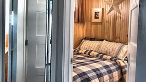 Une chambre avec un grand miroir, une tête de lit en bois, une décoration en forme d’étoile et une couverture à carreaux.