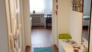 En hall med trägolv, en blå matta, ett vitt skrivbord med en dator och ett element.