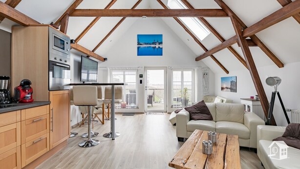 A spacious loft with a kitchen, dining area, and living room, featuring exposed wooden beams and large windows. - At the gates of Hamburg in the old country (Steinkirchen)