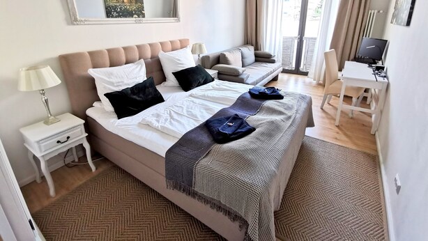 Ein Schlafzimmer mit Bett, einer Couch, einem Schreibtisch und einem Computer.