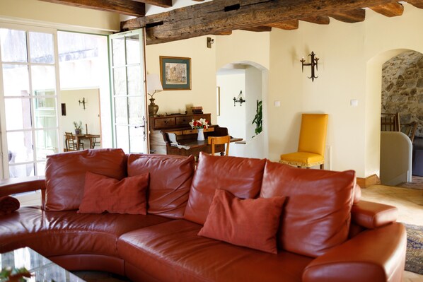 A living room with a leather sofa, wooden furniture, and a stone wall. - Castle in the woods with private SPA 45 min from Paris and Reims, 25 min Disney (Montreuil-Aux-Lions)
