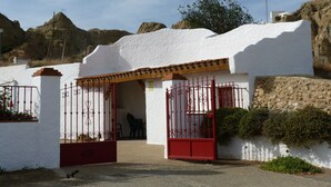 Un edificio blanco con un portón rojo y un pequeño patio.